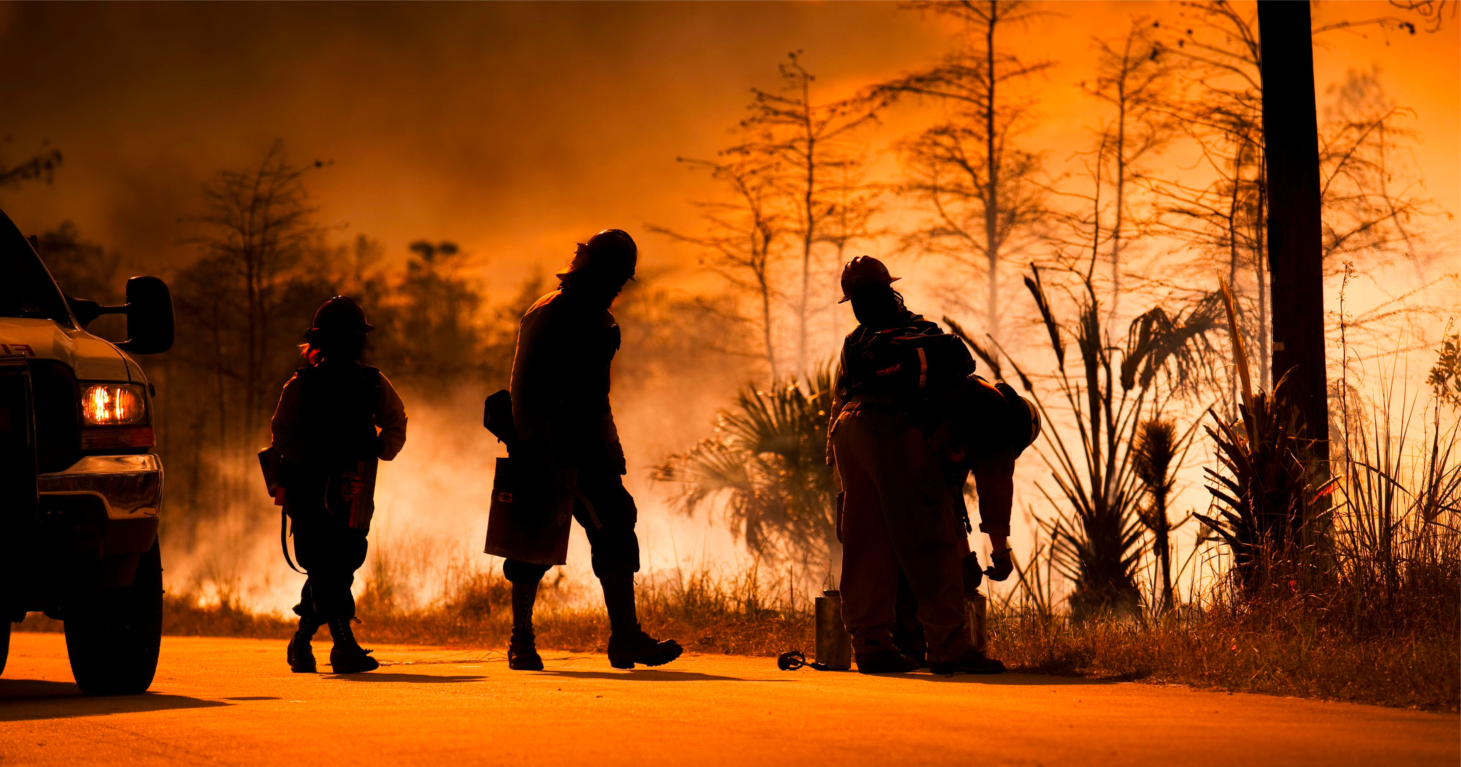 Silhouette of firemen observing and fighting a wildfire